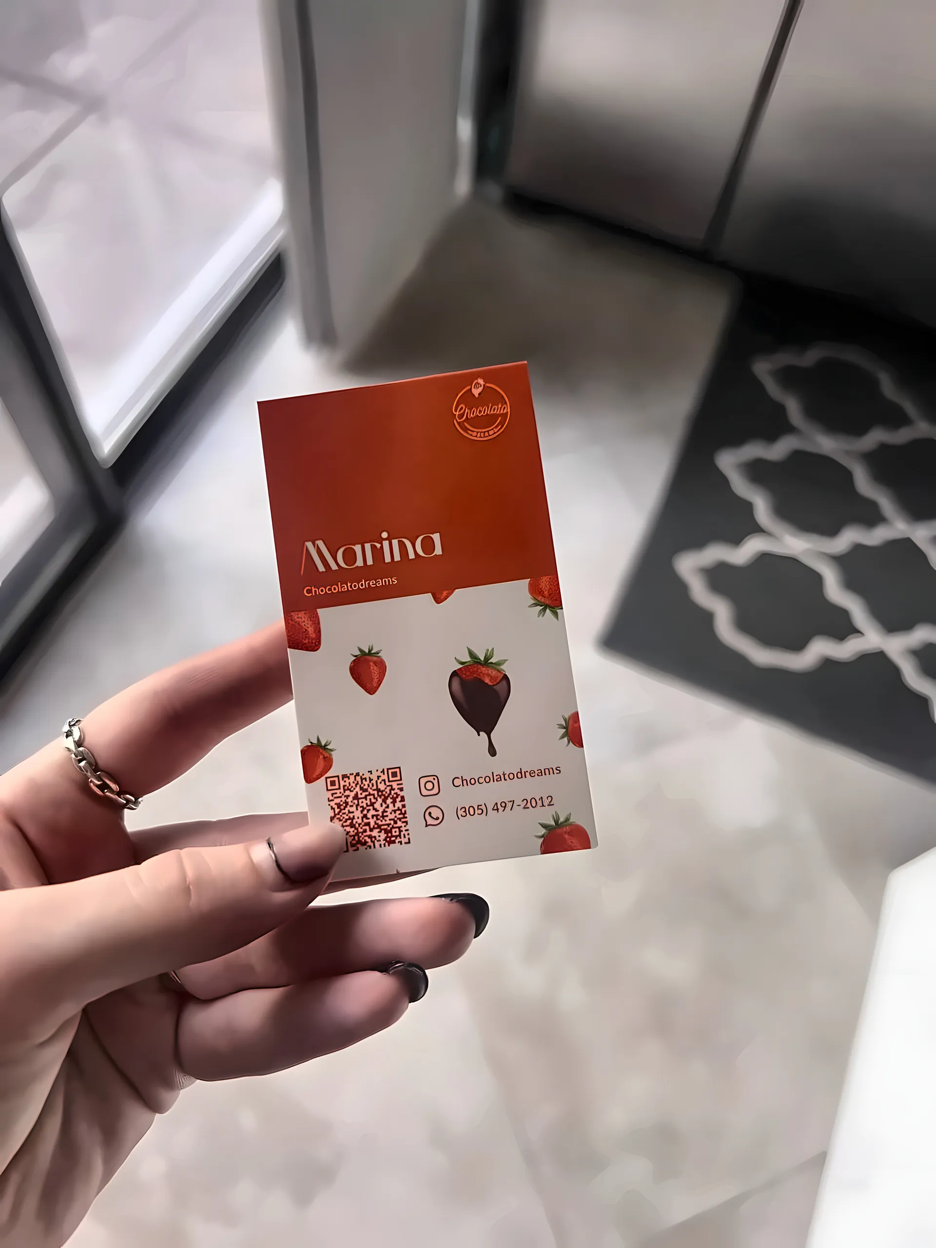 Hand holding the front of a Chocolatodreams business card